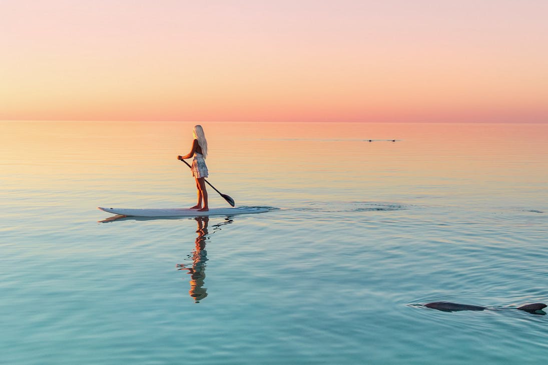A stand up paddle boarder at sunset in Coral Bay